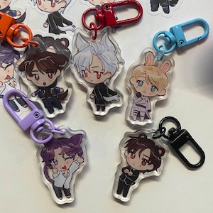 May include: A collection of anime-style acrylic keychains featuring various characters with animal-themed ears and outfits. Each keychain has a different colored clasp, including orange, red, purple, blue, and black. The characters have large eyes and are in various poses.