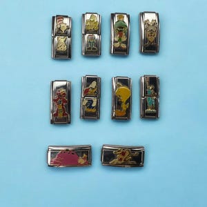 Pode incluir: Doze pulseiras de charms prateadas com vários personagens de desenhos animados. Os charms são coloridos e apresentam personagens como Piu-Piu, Pernalonga e Patolino.