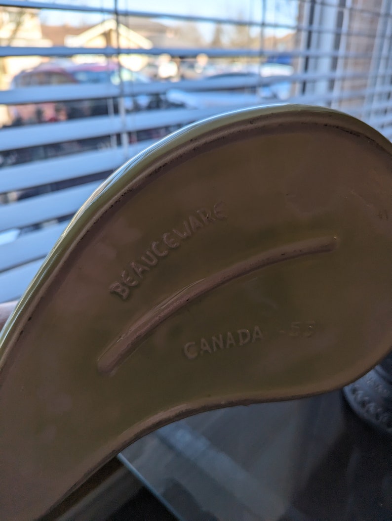 Pu&ograve; includere: Una pirofila in ceramica verde con le parole "BEAUCEWARE CANADA" stampate sul fondo.