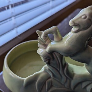 Pu&ograve; includere: Un vaso da fiori in ceramica verde a forma di cavallo con un design a foglie. Il vaso ha una parte superiore rotonda e aperta per la semina.