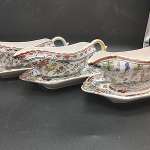 Peut inclure: Trois saucières en céramique blanche avec des motifs floraux dans des tons de rouge, bleu, jaune et vert. Chaque saucière est accompagnée d'une soucoupe assortie.