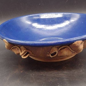 May include: A blue ceramic bowl with a decorative leaf design around the rim.