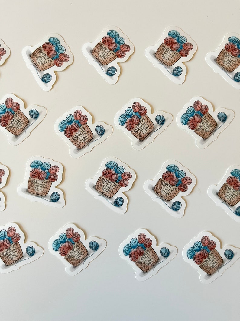 May include: A collection of 16 stickers featuring a basket overflowing with colorful yarn balls. The stickers are arranged in a grid pattern on a white background.