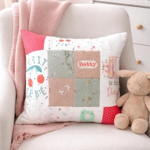 May include: A decorative patchwork cushion in shades of pink, white, and green. The cushion features the name "Dotty" and a cherry design. A soft toy bunny is placed next to the cushion.