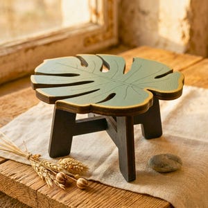 May include: A white ceramic mug with a black handle and the text "But First, Coffee" in a black, handwritten-style font. The mug is on a white surface.