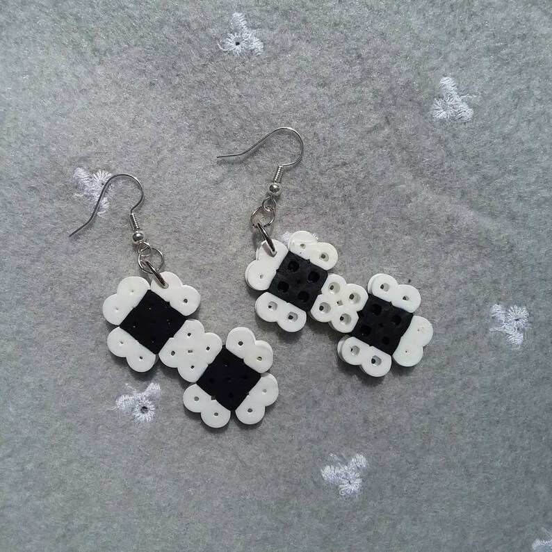 May include: A pair of black and white beaded earrings with silver hooks. The earrings are made of small, round beads that are arranged in a geometric pattern.
