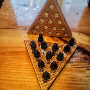 Peut inclure: Un présentoir triangulaire en bois avec 15 petites bouteilles en verre remplies de liquide. Les bouteilles sont disposées en forme de triangle sur le présentoir.