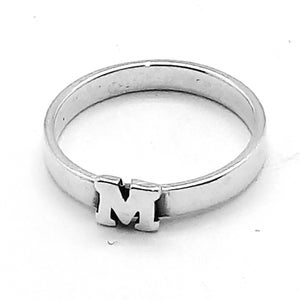 Puede incluir: Un anillo de plata con la letra "M" en él.
