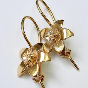 Peut inclure: Une paire de boucles d'oreilles en forme de fleur dor&eacute;es avec un design d&eacute;licat. Les boucles d'oreilles ont une fermeture simple &agrave; crochet.
