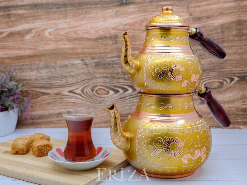 Puede incluir: Un juego de t&eacute; turco de oro y cobre con intrincados dise&ntilde;os florales. El juego incluye una tetera con dos compartimentos y un vaso peque&ntilde;o para servir el t&eacute;.
