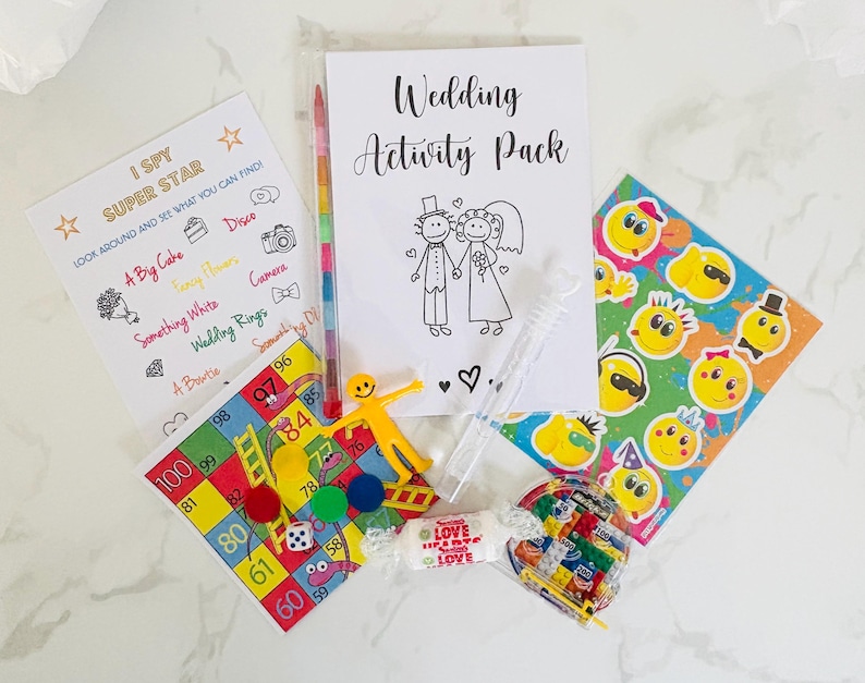 May include: A wedding activity pack with a variety of games and activities, including a "I Spy Super Star" game, a wedding-themed bingo card, a coloring page of a bride and groom, a set of smiley face stickers, and a bubble wand.