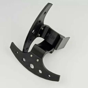 May include: Black plastic bracket with a curved shape and a small rectangular plate with the word "MAD" printed on it.