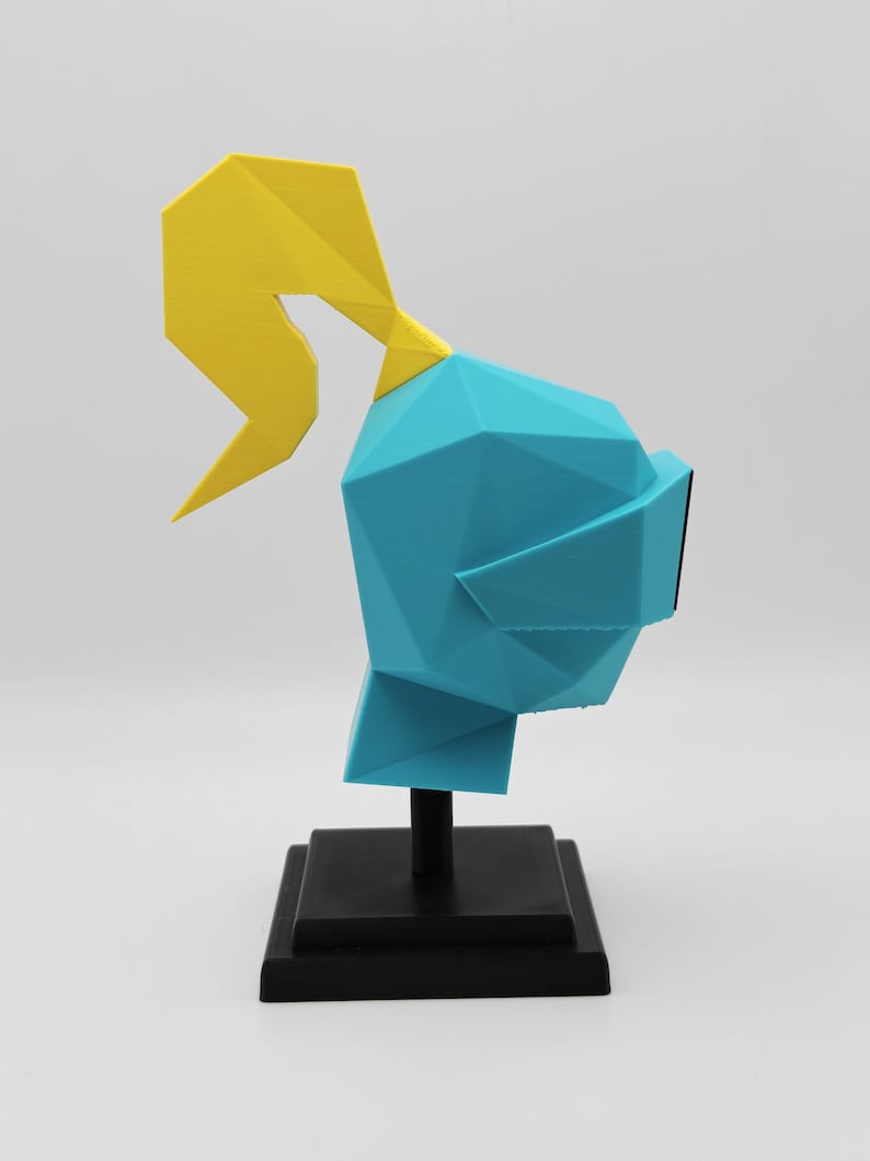 May include: A low-poly style sculpture of a knight helmet in bright cyan with a yellow plume on top. The helmet is mounted on a black vertical post attached to a square black base, creating a geometric display piece for a desk or shelf.