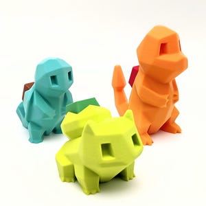 May include: Three colorful 3D-printed figures of popular characters. The figures are in shades of teal, lime green, and orange, each with a geometric, polygonal design. The figures are standing on a white surface.