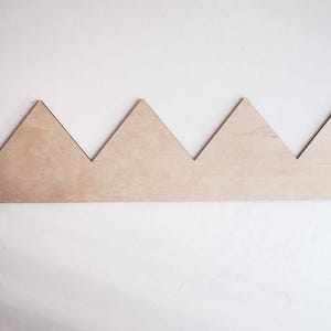 May include: A wooden crown with a series of triangular points, creating a jagged, mountain-like shape.