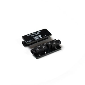 Peut inclure: Un convertisseur MIDI TRS A/B noir avec une étiquette noire et blanche indiquant "MIDI TRS A/B Converter v1.0".