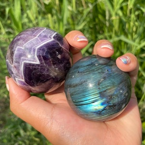 May include: Two polished crystal spheres, one amethyst with a chevron pattern and one labradorite with iridescent blue and green hues.