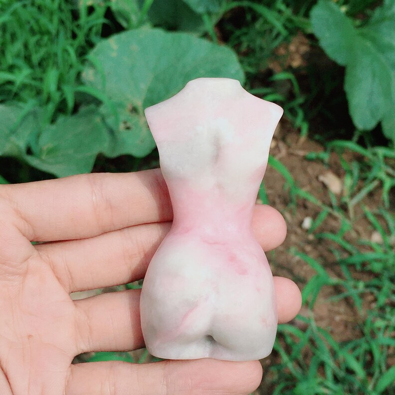 Op de afbeelding: Een wit en roze keramisch beeld van een menselijk torso.