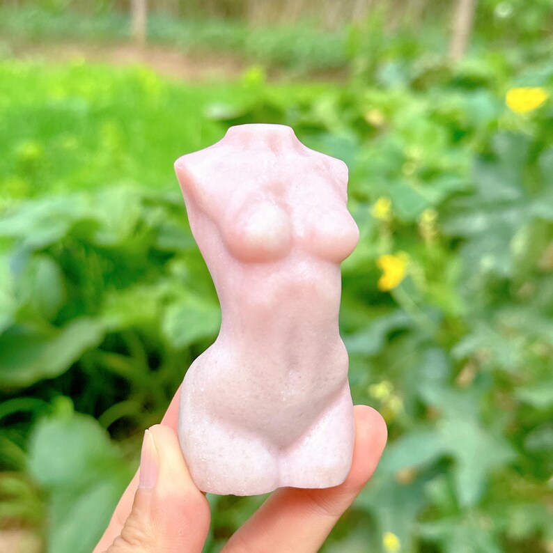 Op de afbeelding: Een roze, gladde en gedetailleerde sculptuur van een menselijk torso.