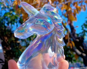 May include: A clear iridescent glass unicorn sculpture with a rainbow sheen. The sculpture is a head and neck of a unicorn with a horn.