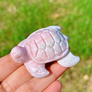Op de afbeelding: Een roze en wit gesneden zeeschildpad beeldje gemaakt van gepolijst steen. De schildpad heeft een gedetailleerde schelp en een gladde, glanzende afwerking.