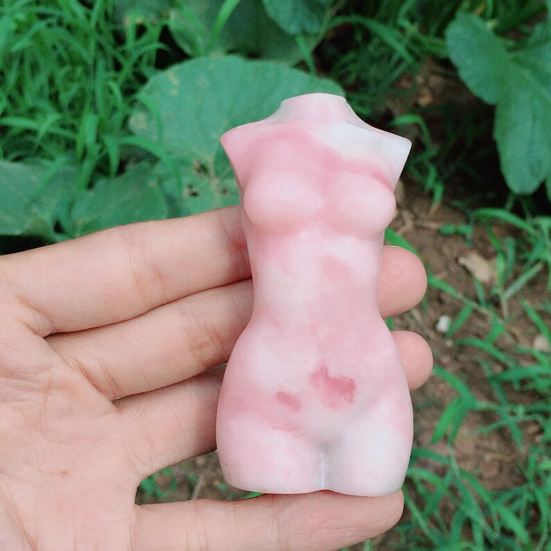 Op de afbeelding: Een roze en witte torso-sculptuur gemaakt van hars. Het beeld heeft een gladde, gepolijste afwerking en een draaiende patroon.