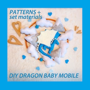 May include: DIY Dragon Baby Mobile pattern and materials set. The mobile features a blue felt dragon with white wings, gray felt clouds, and wooden hearts.