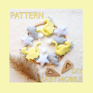 May include: DIY baby mobile pattern featuring yellow felt dragons, gray felt clouds and stars, and wooden hearts. The pattern includes instructions for creating a mobile with a wooden hoop.
