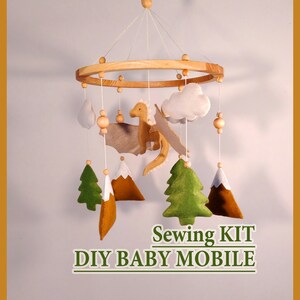 May include: A DIY baby mobile sewing kit featuring a wooden ring, felt clouds, a felt dragon, and felt trees. The kit includes instructions for creating a whimsical mobile for a nursery.