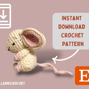 Könnte beinhalten: Eine gehäkelte Maus in Creme und Rosa, mit großen Ohren und einem langen Schwanz. Das Bild enthält den Text "INSTANT DOWNLOAD CROCHET PATTERN" und das Etsy-Logo. Der Hintergrund ist ein gedämpftes Rosa.