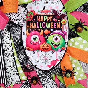 Puede incluir: Una corona de Halloween con un &oacute;valo central con monstruos de dibujos animados y el texto "HAPPY HALLOWEEN". La corona est&aacute; decorada con cintas rosas, verdes, naranjas y negras, telara&ntilde;as y ara&ntilde;as brillantes. Una decoraci&oacute;n festiva y colorida.