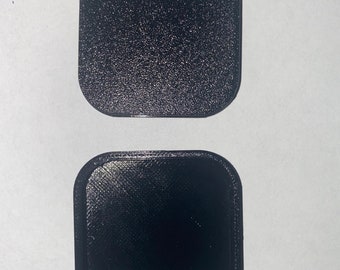 May include: Two black square-shaped plastic containers. The top container is smooth and the bottom container has a raised edge.