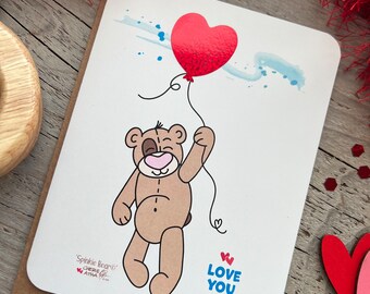 Carte de correspondance avec un ours en peluche tenant un ballon coeur en vinyle rouge scintillant, message « Je t'aime », personnage original dessiné à la main, envoi d'amour