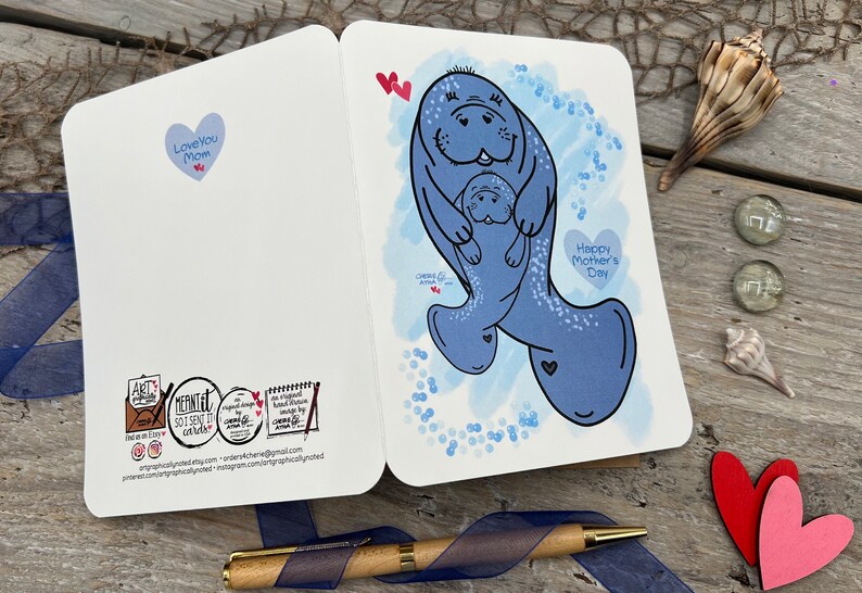 This picture shows the front and back of the card. A Mothers Day greeting card with a blue watercolor background and a illustration of two manatees. It also has bubbles all around, to show they are swimming. The larger momma manatee is holding the smaller manatee in her flippers. The card has the text Happy Mothers Day in a heart shape on the front. It has the text Love You Mom in a heart shape on the back of the card along with my logos.