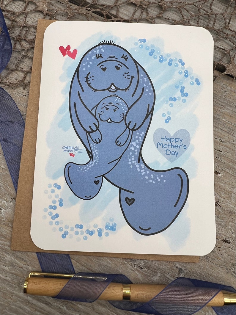 This card is an original hand drawn image of a momma and young manatee. The greeting card has a blue watercolor background and blue bubbles. The bigger manatee represents the mother and the smaller one represents a baby or younger manatee. The text on the card reads Happy Mothers Day.