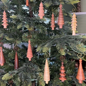 May include: A Christmas tree decorated with wooden ornaments shaped like trees. The ornaments are in shades of brown, pink, and beige.