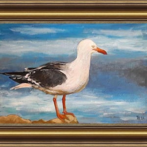 Może przedstawiać: Obraz olejny przedstawiający mewę na skale, na tle błękitnego i białego nieba. Ptak ma białą głowę, czarno-białe skrzydła oraz pomarańczowe nogi i dziób. Dzieło sztuki jest oprawione w złotą ramę.