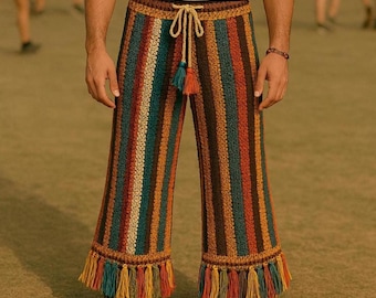 May include: Crocheted pants with vertical stripes in shades of brown, orange, teal, and cream. The pants have a drawstring waist and fringe detailing at the hem. The pants are worn with brown shoes.