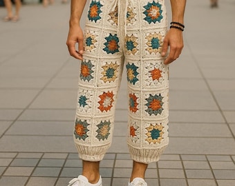 Puede incluir: Pantalones de crochet color crema con cintura con cordón y patrones cuadrados coloridos. Los cuadrados presentan diseños florales en naranja, verde azulado y amarillo. Los pantalones tienen un puño acanalado en el tobillo y se usan con zapatillas blancas.