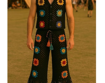 May include: Black crochet vest and pants set with colorful flower appliqués. The vest has a button-up front and the pants have a drawstring waist and fringe at the hem. A straw hat and sunglasses complete the look.