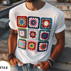 Pode incluir: Camiseta branca com um design de padrão de quadrados de crochê coloridos. Os quadrados são dispostos em uma grade de 3x3 e apresentam várias cores, incluindo vermelho, azul, verde, amarelo e rosa.