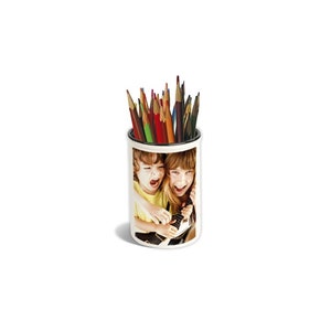 Peut inclure: Porte-crayons en céramique blanche avec une photo de deux enfants riant et tenant une guitare. Le porte-crayons est rempli de crayons de couleur.