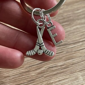May include: Silver keyring with a hockey stick charm and a letter E charm.