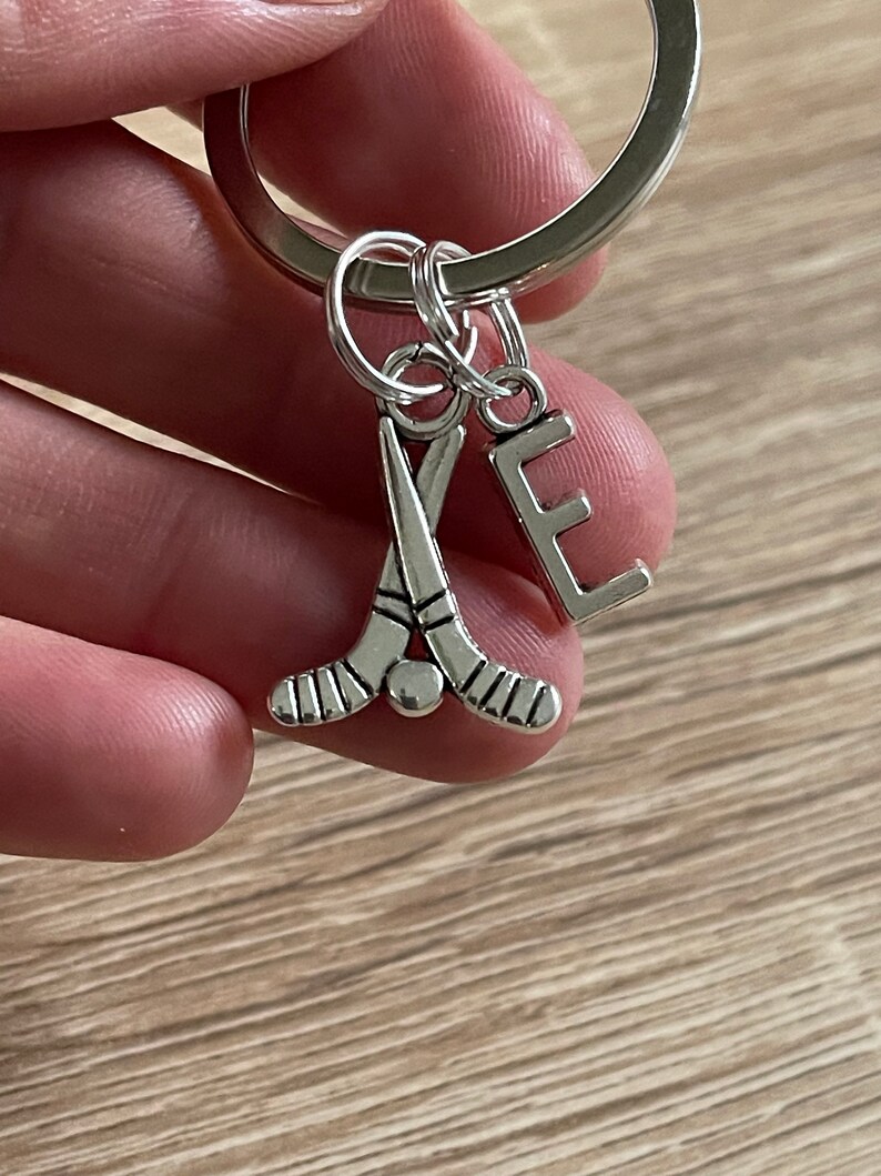 May include: Silver keyring with a hockey stick charm and a letter E charm.