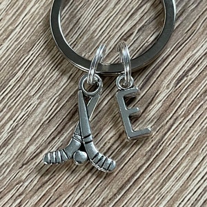 May include: Silver keyring with a hockey stick charm and a letter E charm.