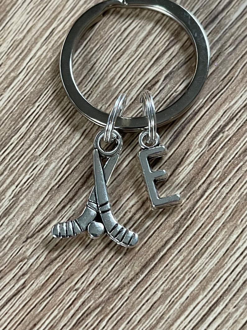 May include: Silver keyring with a hockey stick charm and a letter E charm.