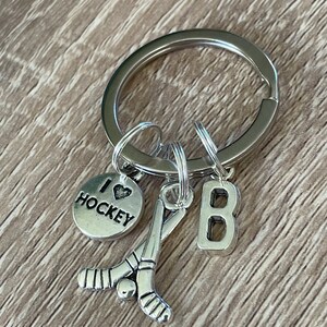 May include: Silver keyring with a hockey stick charm, a charm that says "I love hockey", and a charm with the letter "B".