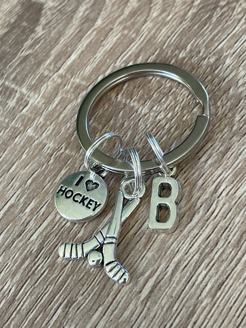 May include: Silver keyring with a hockey stick charm, a charm that says "I love hockey", and a charm with the letter "B".