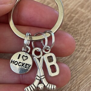 May include: Silver keyring with a hockey stick charm, a charm that says "I love hockey", and a charm with the letter "B".