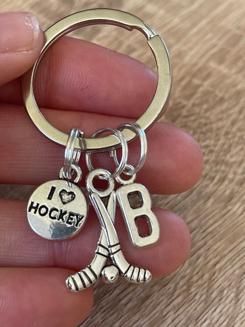 May include: Silver keyring with a hockey stick charm, a charm that says "I love hockey", and a charm with the letter "B".